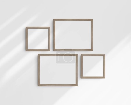 Foto de Conjunto de maquetas de pared Gallery, 4 marcos de madera natural. Maqueta de marco limpia, moderna y minimalista. Dos marcos horizontales y dos cuadrados, 14x11 (14: 11), 8x8 (1: 1) pulgadas, en una pared blanca con sombras. - Imagen libre de derechos