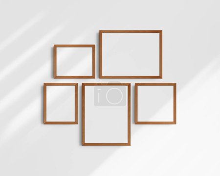 Foto de Conjunto de maquetas de pared Gallery, 5 marcos de madera de cerezo. Una maqueta moderna y minimalista. Dos marcos horizontales, dos marcos verticales, y un marco cuadrado, 12x16 (3: 4), 16x12 (4: 3), 8x10 (4: 5), 10x8 (5: 4), 10x10 (1: 1) pulgadas, en una pared blanca con sombras. - Imagen libre de derechos