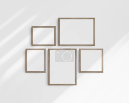 Foto de Conjunto de maquetas de pared Gallery, 5 marcos de madera natural. Una maqueta moderna y minimalista. Dos marcos horizontales, dos marcos verticales, y un marco cuadrado, 12x16 (3: 4), 16x12 (4: 3), 8x10 (4: 5), 10x8 (5: 4), 10x10 (1: 1) pulgadas, en una pared blanca con sombras. - Imagen libre de derechos