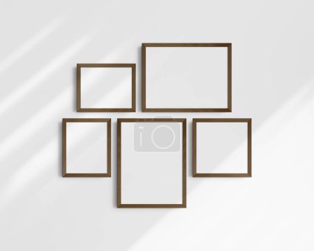 Foto de Conjunto de maquetas de pared Gallery, 5 marcos de madera de nogal marrón oscuro. Una maqueta moderna y minimalista. Dos marcos horizontales, dos marcos verticales, y un marco cuadrado, 12x16 (3: 4), 16x12 (4: 3), 8x10 (4: 5), 10x8 (5: 4), 10x10 (1: 1) pulgadas, en una pared blanca. - Imagen libre de derechos