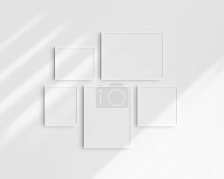 Foto de Conjunto de maquetas de pared Gallery, 5 marcos blancos. Maqueta de marco limpia, moderna y minimalista. Dos marcos horizontales, dos marcos verticales, y un marco cuadrado, 12x16 (3: 4), 16x12 (4: 3), 8x10 (4: 5), 10x8 (5: 4), 10x10 (1: 1) pulgadas, en una pared blanca con sombras. - Imagen libre de derechos