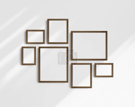 Téléchargez les photos : Ensemble de maquettes murales Galerie, 7 cadres en bois de noyer brun foncé. Modèle de cadre propre, moderne et minimaliste. Trois cadres horizontaux, et quatre cadres verticaux, 5x7 (5 : 7), 7x5 (7 : 5), 8x10 (4 : 5), 12x15 (4 : 5), 15x12 (5 : 4) pouces, sur un mur blanc avec des ombres. - en image libre de droit