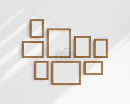 Foto de Conjunto de maquetas de pared Gallery, 8 marcos de madera de cerezo. Maqueta de marco limpia, moderna y minimalista. Cinco marcos verticales, y tres horizontales, 4x6 (2: 3), 6x4 (3: 2), 5x7 (5: 7), 7x5 (7: 5), 8x10 (4: 5), 10x8 (5: 4) pulgadas, en una pared blanca con sombras. - Imagen libre de derechos
