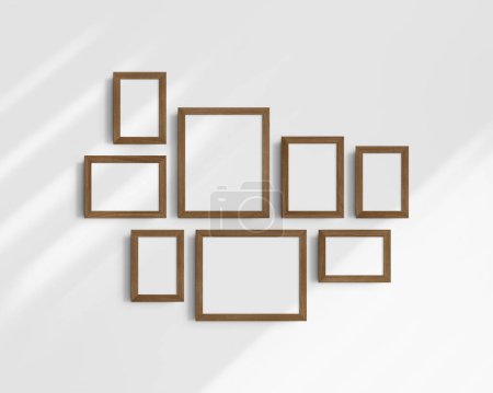 Foto de Conjunto de maquetas de pared Gallery, 8 marcos de madera de nogal marrón. Maqueta de marco limpia, moderna y minimalista. Cinco marcos verticales, y tres horizontales, 4x6 (2: 3), 6x4 (3: 2), 5x7 (5: 7), 7x5 (7: 5), 8x10 (4: 5), 10x8 (5: 4) pulgadas, en una pared blanca con sombras. - Imagen libre de derechos