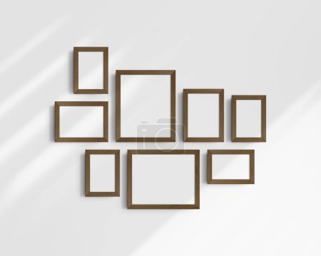 Foto de Conjunto de maquetas de pared Gallery, 8 marcos de madera de nogal marrón oscuro. Una maqueta moderna y minimalista. Cinco marcos verticales, y tres horizontales, 4x6 (2: 3), 6x4 (3: 2), 5x7 (5: 7), 7x5 (7: 5), 8x10 (4: 5), 10x8 (5: 4) pulgadas, en una pared blanca con sombras. - Imagen libre de derechos