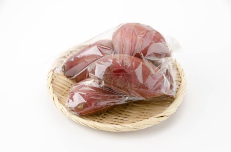 Téléchargez les photos : Japanese sweet potatos(silk sweet) in plastic bag on white background - en image libre de droit