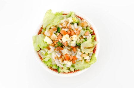 colorful fresh vegetable salad with spicy sausage and chikuwa in a white bowl on white background.