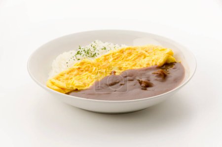 Riz au curry japonais garni d'omelette dans un plat blanc sur fond blanc.