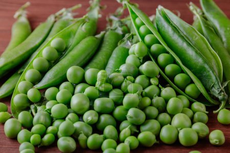 Green pea and pea pods. Pea on wooden table. Closeup of fresh pea. Pea pod with beans.