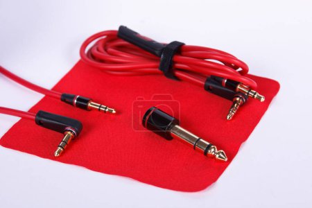 Cables and connectors for headphones on red cloth. Different variations of audio jack connectors.