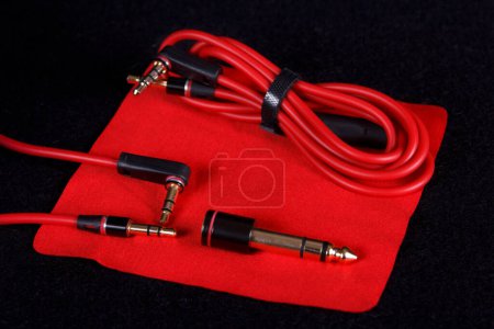 Cables and connectors for headphones on red cloth. Different variations of audio jack connectors.