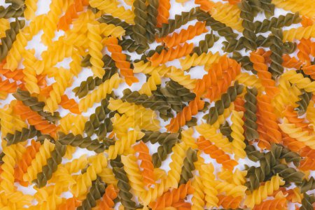 Heap of three-colored pasta on white background. Close-up. Top view.