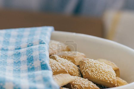 Biscuits faits maison fraîchement cuits au four avec sésame recouvert d'une serviette dans un bol.