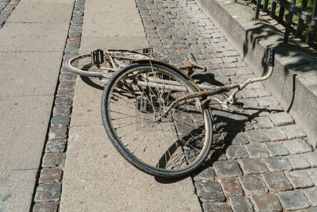 Foto de Una vieja bicicleta sucia yace en medio de la calle. - Imagen libre de derechos