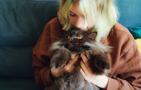 Teenage girl hugging cat at home.