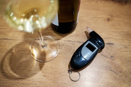 Portable breathalyzer and a glass of white wine.