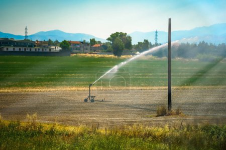 Foto de Watering machine waters a field during a drought period. - Imagen libre de derechos