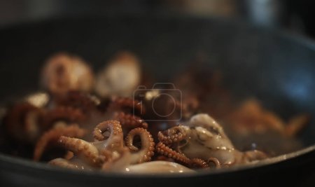 Foto de Cooking small octopuses in frying pan. - Imagen libre de derechos