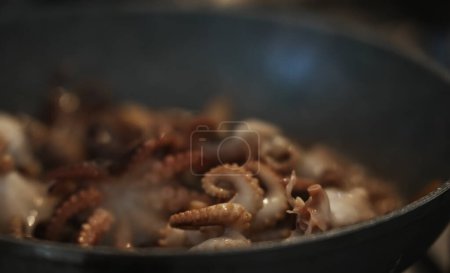 Foto de Cooking small octopuses in frying pan. - Imagen libre de derechos