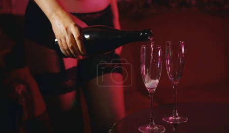 Téléchargez les photos : Woman pouring champagne in glasses in strip club. - en image libre de droit