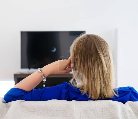 Téléchargez les photos : Une femme attend qu'un film se charge à la télé. Connexion Internet lente. - en image libre de droit