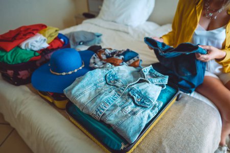 Photo for Woman packs her clothes into a suitcase. Preparing for vacation. - Royalty Free Image