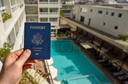 Homme détenant un passeport américain dans le contexte d'un hôtel de luxe.