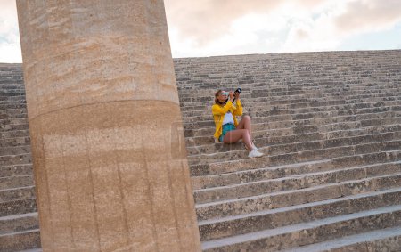 Téléchargez les photos : Une touriste avec une caméra dans l'Acropole en excursion. - en image libre de droit