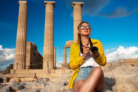 Une touriste avec une caméra dans l'Acropole en excursion.