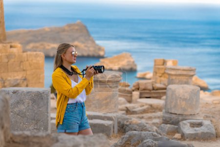 Une touriste avec une caméra dans l'Acropole en excursion.