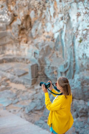 Photo for Female tourist takes photographs of Exedra at the entrance to the Acropolis of Lindos. - Royalty Free Image