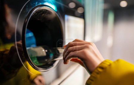Woman puts bottle in automatic bottle recycling machine. Reverse vending recycling machine.