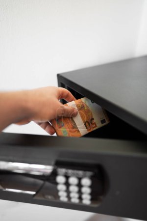 Man puts or takes euro banknotes from a safe.