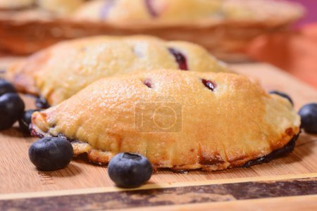 Photo for Several blueberry hand pies on a serving board and in a serving basket - Royalty Free Image