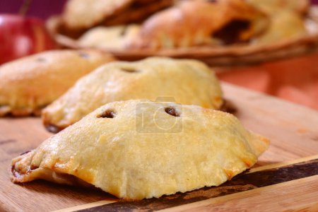 Photo for Several apple hand pies on a serving board and in a serving basket - Royalty Free Image