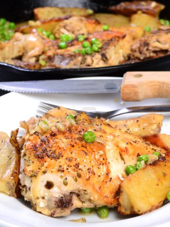 Téléchargez les photos : Vésuve de poulet servi dans une assiette avec pommes de terre rôties et pois frais dans une sauce au citron à l'ail - en image libre de droit