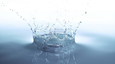 Téléchargez les photos : Couronne éclaboussure d'eau isolée sur fond bleu doux. Mouvement de gel de l'eau qui explose dans l'air. - en image libre de droit