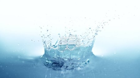 Foto de Corona de salpicadura de agua aislada sobre fondo azul suave. Congelar el movimiento del agua explotando en el aire. - Imagen libre de derechos