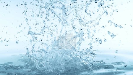 Foto de Salpicadura de agua aislada sobre fondo azul suave. Congelar el movimiento del agua explotando en el aire. - Imagen libre de derechos
