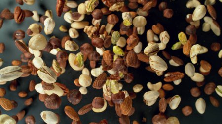 Téléchargez les photos : Freeze motion of flying mix of nuts. Studio shot, colored background. - en image libre de droit