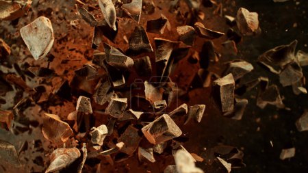 Foto de Congelar el movimiento del grupo volador de piezas de chocolate crudo. Aislado sobre fondo negro - Imagen libre de derechos