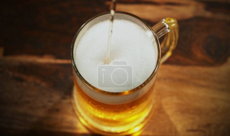 Téléchargez les photos : Glass of light beer pouring on wooden table. Studio shot with isolated glass of beer. - en image libre de droit