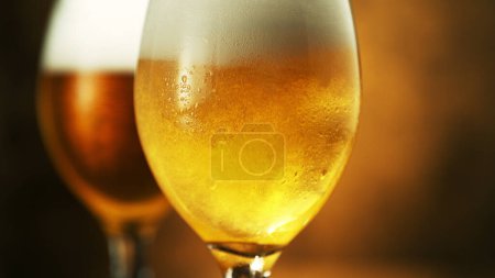 Foto de Glass of light beer on dark golden background. Isolated glass of beer, macro shot. - Imagen libre de derechos
