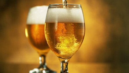 Téléchargez les photos : Glass of pouring light beer on dark golden background. Isolated glass of beer. - en image libre de droit