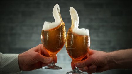 Photo for Two glasses of beer in cheers gesture, splashing out. Isolated on shabby background. - Royalty Free Image