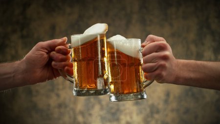 Téléchargez les photos : Two glasses of beer in cheers gesture, splashing out. Isolated on shabby background. - en image libre de droit