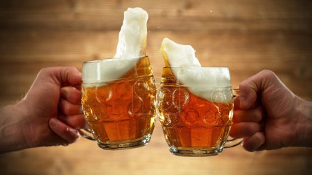 Photo for Two glasses of beer in cheers gesture, splashing out. Isolated on wooden background. - Royalty Free Image