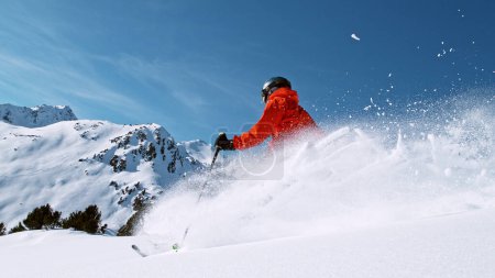 Foto de Esquiador de paseo libre corriendo colina abajo. La nieve en polvo vuela en el aire. - Imagen libre de derechos