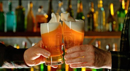 Téléchargez les photos : Vue rapprochée d'un deux verres de bière dans les mains. Verres à bière cliquetis au bar ou pub. - en image libre de droit