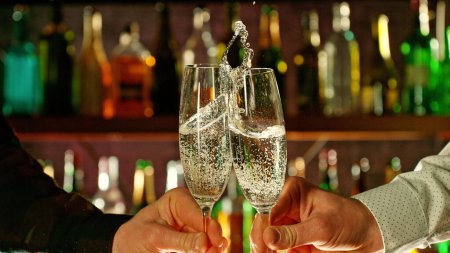 Téléchargez les photos : Close-up view of a two glasses of champagne in hands. Glasses clinking at bar or pub. - en image libre de droit